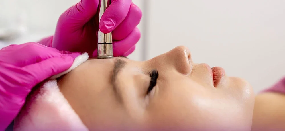 Doctor performing microdermabrasion on woman's forehead