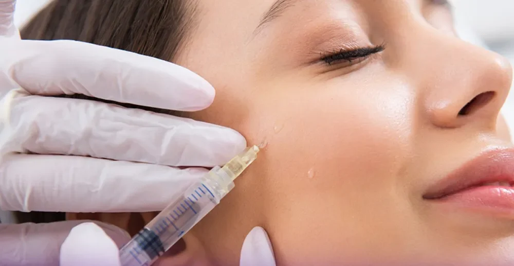 صورت دختری که لبخند زده است و پزشکی که با سرنگ به گونه راست او بوتاکس تزریق می کند