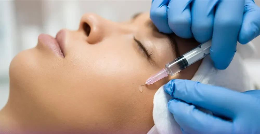 پزشکی که به گونه دختر بوتاکس تزریق می کند در حالی که یک قطره از بوتاکس از گونه دختر به سمت پایین چکیده است - بوتاکس گونه