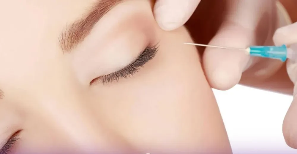 A person whose eyes closed and the doctor's hands are injecting Botox under his eyes and the other hand on the face of the person