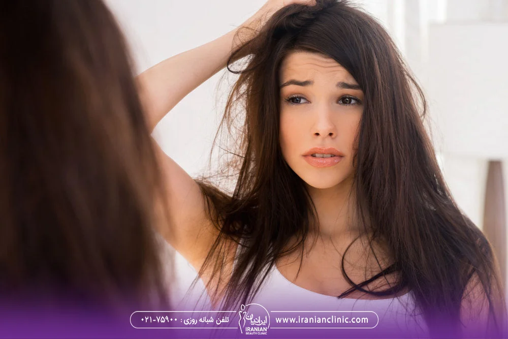 زن جوان که موهای خود را در آینه می بیند و نگران است - درمان ریزش مو هورمونی