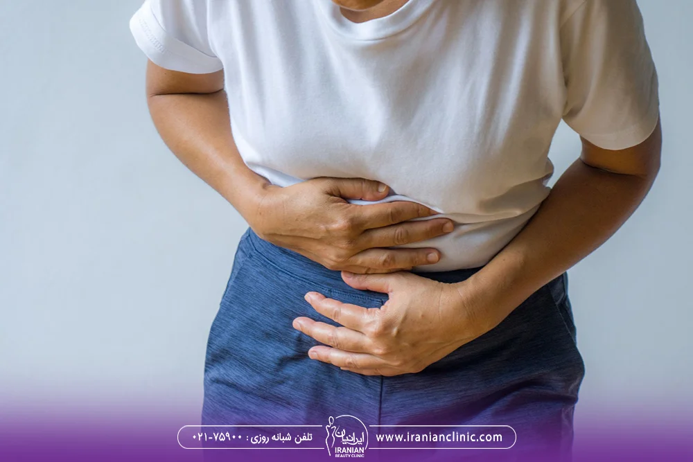 عکس یک زن که شکم خود را گرفته است و دل درد دارد