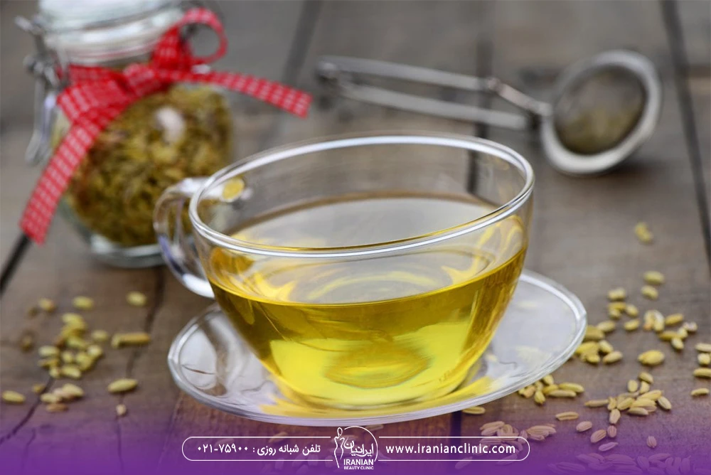 یک لیوان دمنوش رازیانه روی میز که در کنار آن دانه های رازیانه ریخته شده است
