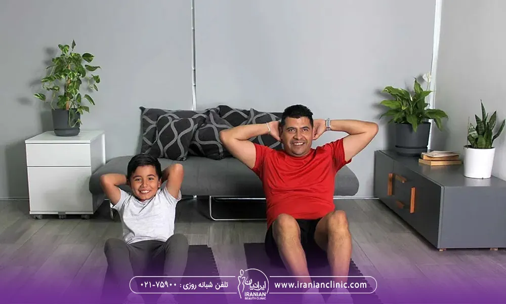 پدر و پسری که در کنار هم نشساه اند و در حال ورزش کردن هستند.