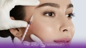 پزشکی که به صورت دختر جوان پروفایلو تزریق می کند و سرنگ را کنار گونه دختر نگه داشته است - ماندگاری ژل پروفایلو