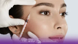 پزشکی که به صورت دختر جوان پروفایلو تزریق می کند و سرنگ را کنار گونه دختر نگه داشته است - ماندگاری ژل پروفایلو