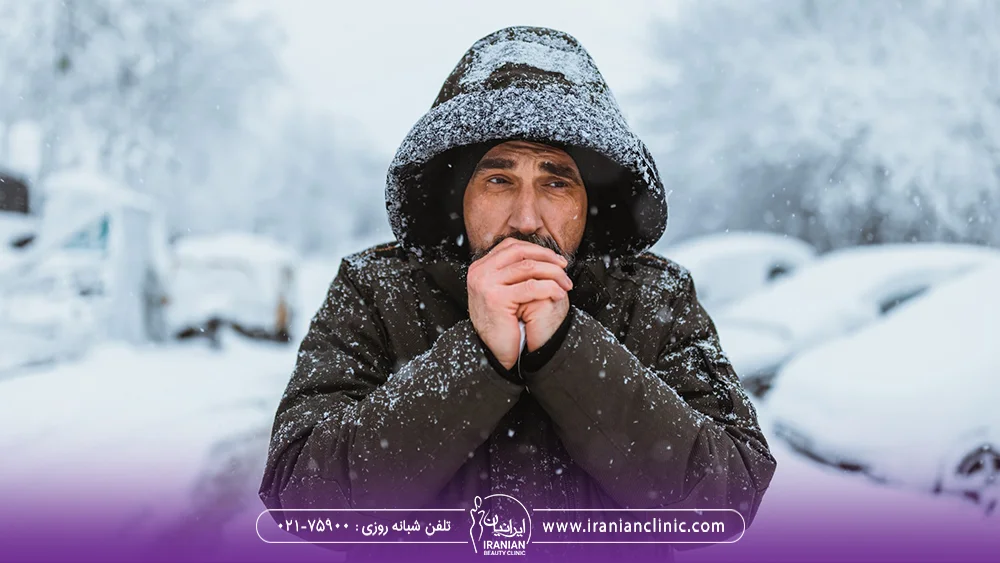 مردی که در زمستان احساس سرما می کند و لباس زمستانی به تن دارد
