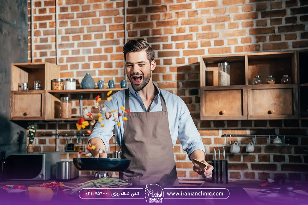 مرد با موهای پرپشت که لبخند می زند و مشغول پختن غذا است