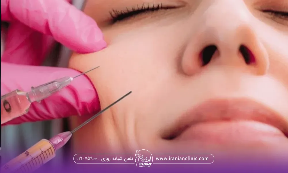 صورت خانم از نزدیک که دستان دکتر با دستکش صورتی در حال تزریق چربی به صورت وی است