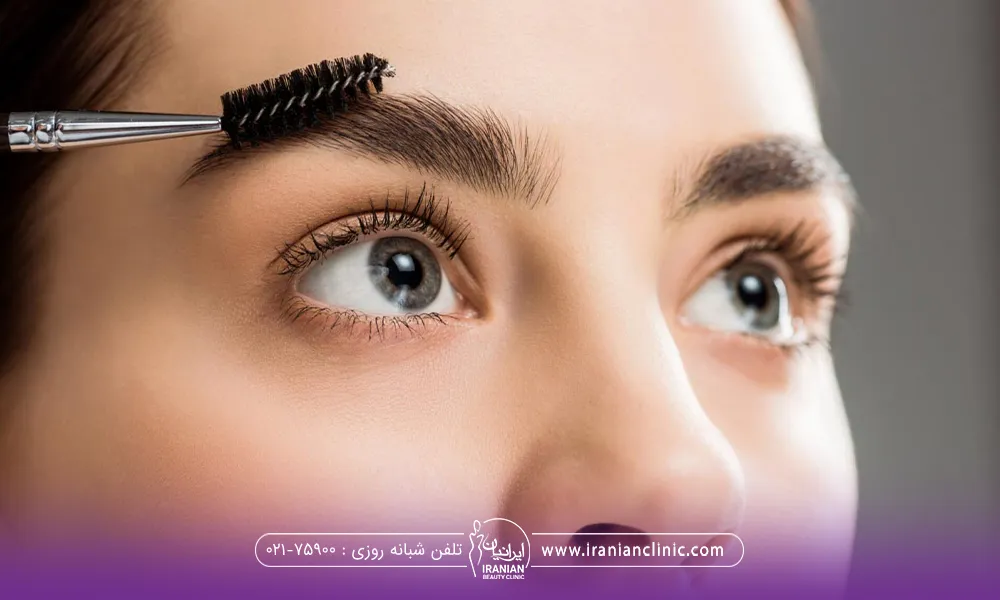 دختری که ابروهای بلندی دارد و با برس ابروی راست خود را مرتب می کند - کاشت ابرو سعادت آباد
