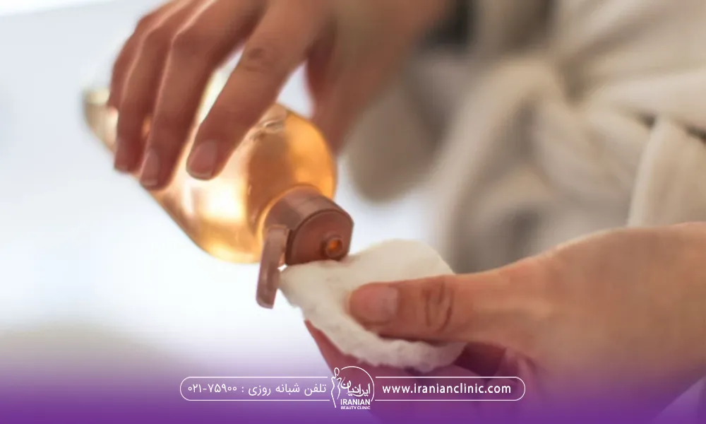 دست فردی که در حال ریختن سرم روی پد برای شستشوی صورت بعد از تزریق چربی است