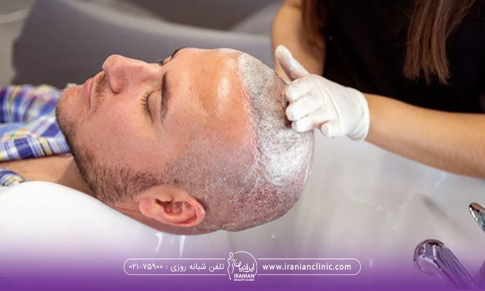 آقایی که چشمان خود را بسته و دستان فردی که در حال شستن سر او میباشد