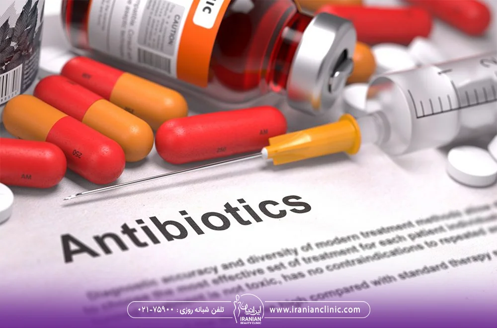 چند کپسول و آمپولی روی یک برگه کاغذ که روی کاغذ کلمه antibiotics نوشته شده - نکروز کاشت مو