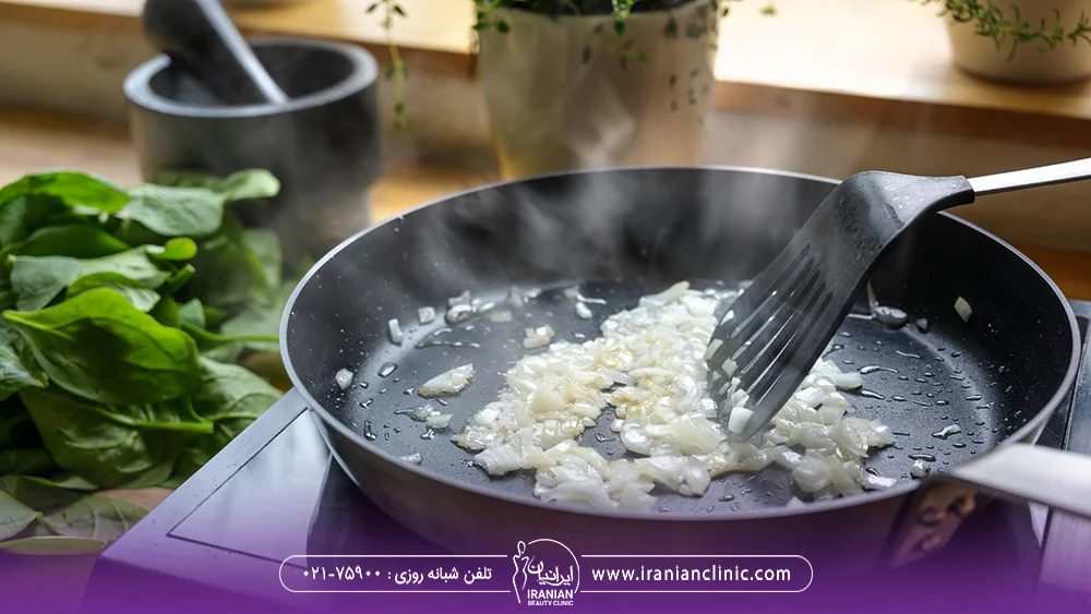 یک ماهیتابه روی گاز که فردی در آن پیاز داغ درست می کند