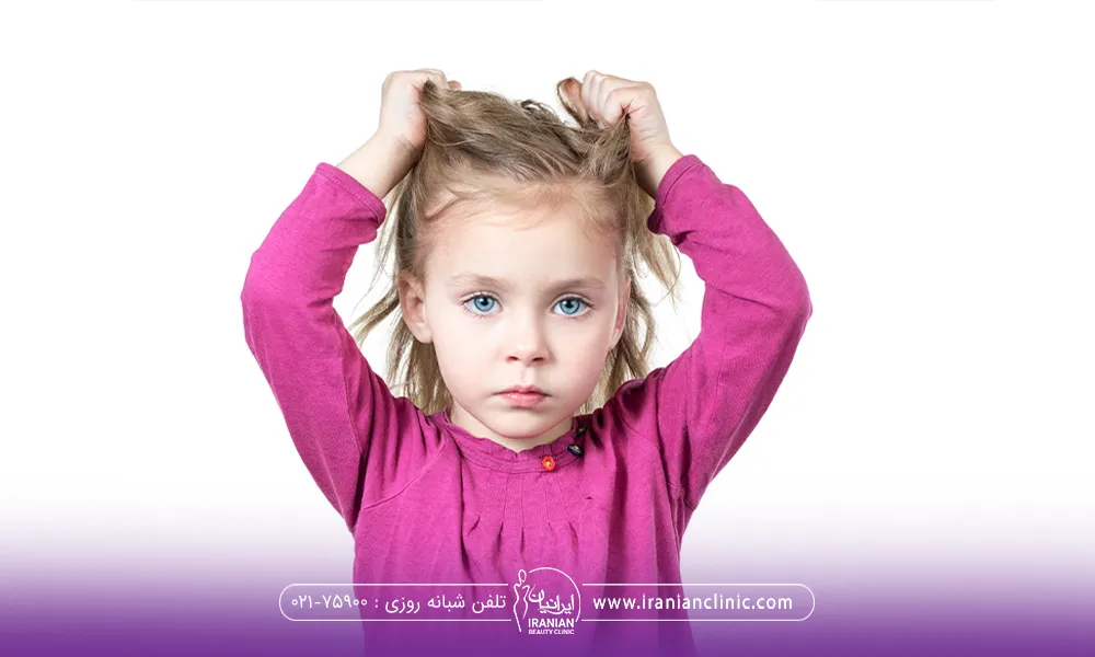 کودکی با چشم آبی که به رو به رو نگاه می کند و با دو دستش موهایش را گرفته است