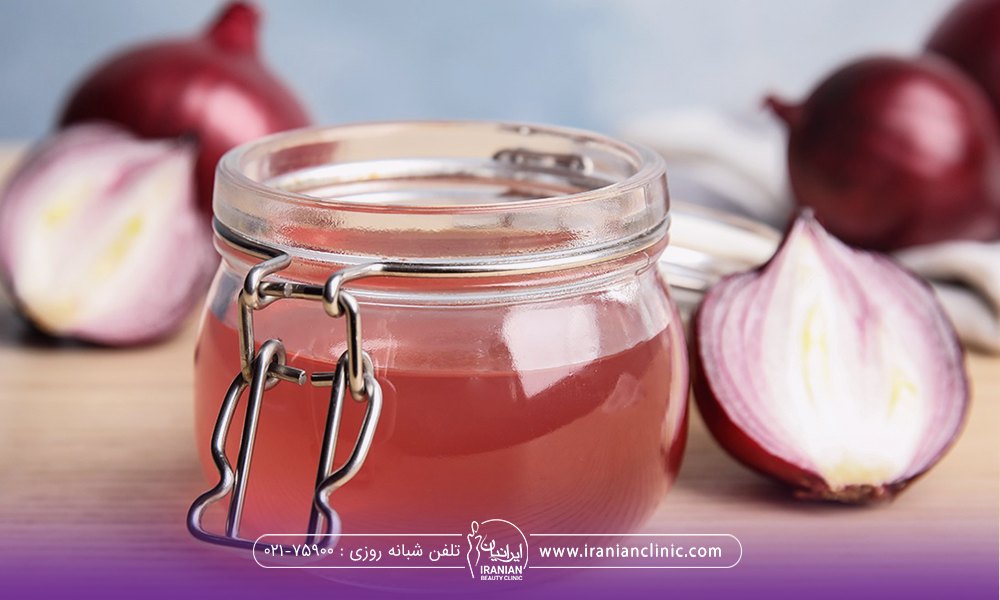 یک شیشه که داخل آن آب پیاز ریخته شده و چند تکه پیاز که در پشت تصویر مشخص است